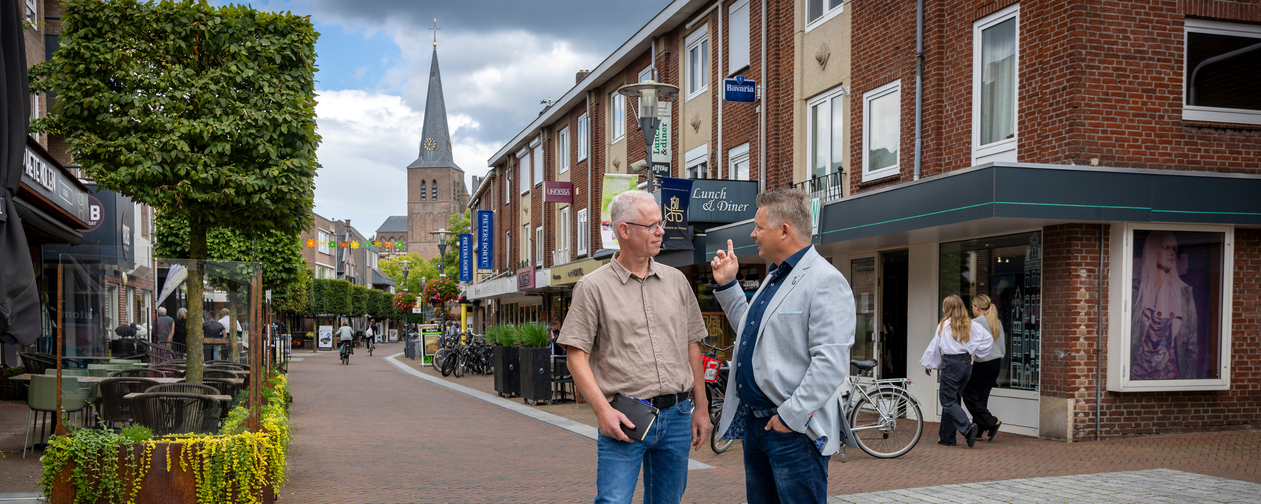 De twee medewerkers staan in het centrum van Deurne en zijn met elkaar in gesprek.