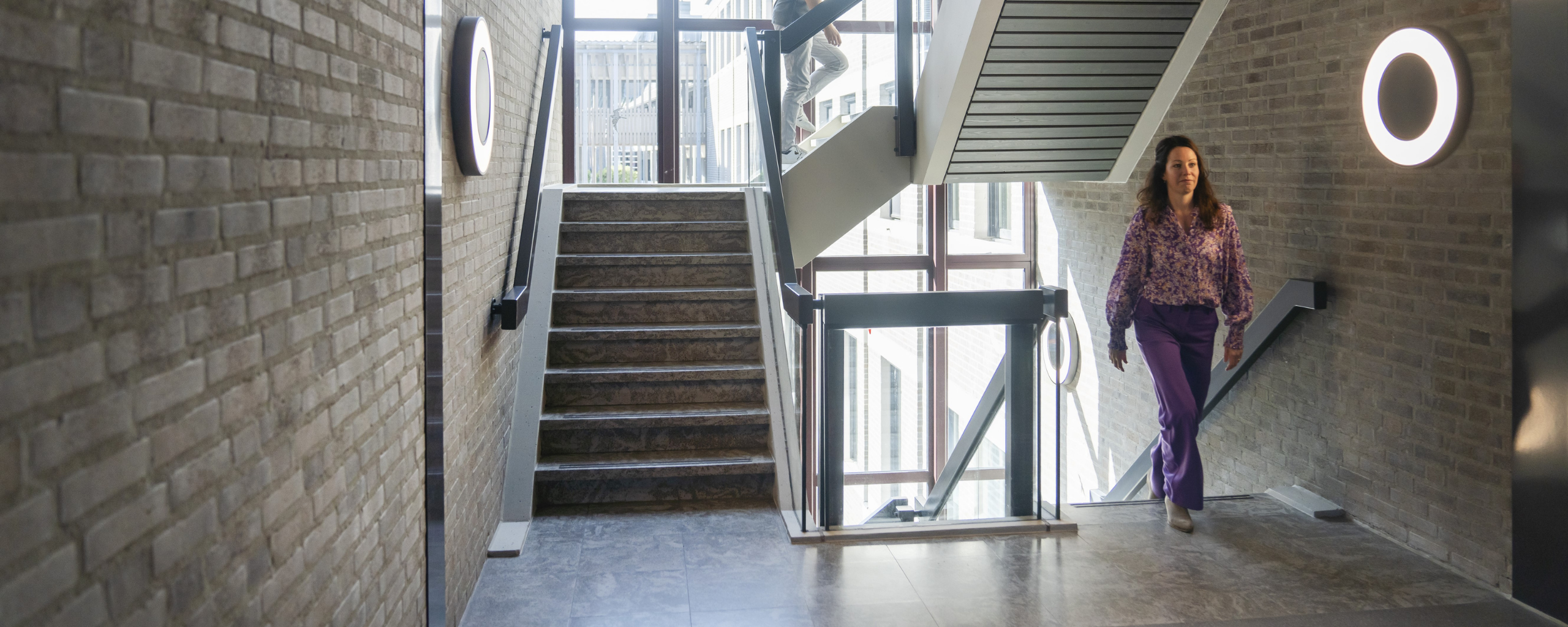 Twee medewerkers lopen de trap op in het Huis voor de samenleving.