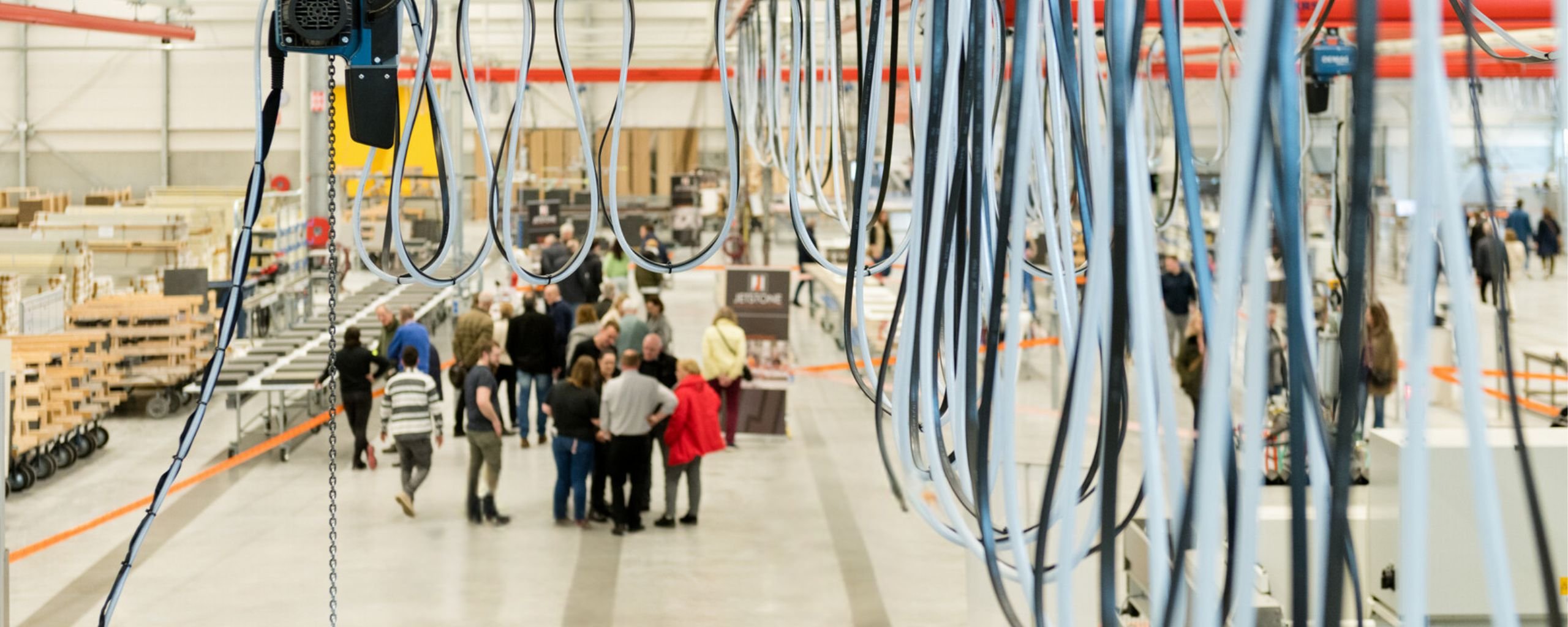 Impressie van een bedrijfsbezoek in Deurne, een groepje mensen in een grote fabriekshal