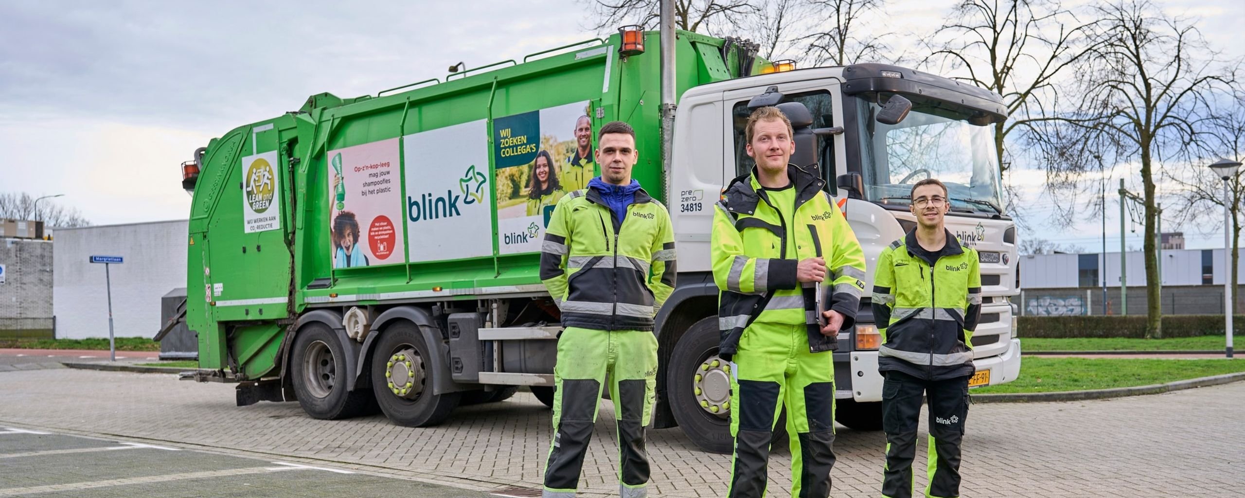 Drie medewerkers van Blink voor één van de afval ophaalwagens van het bedrijf.