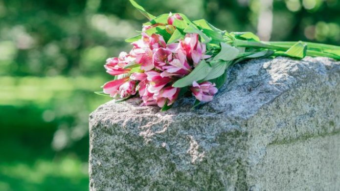 Nieuwsteaser bericht belanghebbenden begraafplaatsen gezocht, foto grafsteen met bloemen