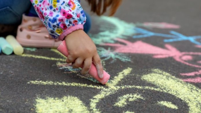 Teaserafbeelding straatspeeldag, kind maakt tekening met krijt op een straat