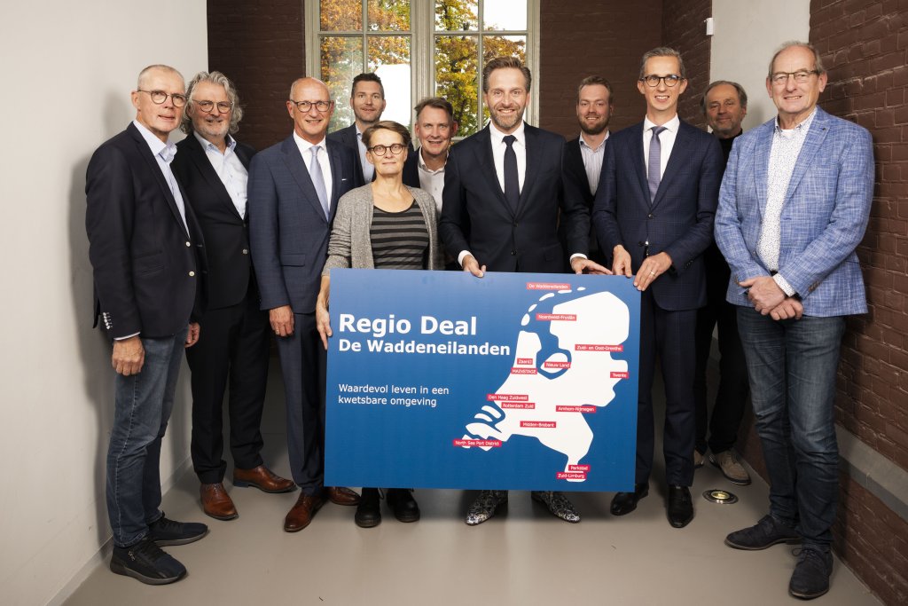 Personen op de foto (van links naar rechts):  Rikus Kieft, wethouder gemeente Texel  Roel de Jong, wethouder gemeente Vlieland  Rob van der Zwaag, waarnemend burgemeester gemeente Texel  Theo Faber, wethouder gemeente Ameland  Gea van Essen, wethouder gemeente Terschelling  Michiel Schrier, burgemeester Vlieland en voorzitter Programma Waddeneilanden  Minister Hugo de Jonge (Binnenlandse Zaken, Koninkrijksrelaties, Volkshuisvesting en Ruimtelijke Ordening)  Marijn Oud, Programmamanager Regio Deal De Waddene