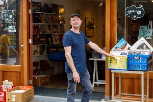 Bas Benraad staat voor zijn winkel met collectie vinyl platen