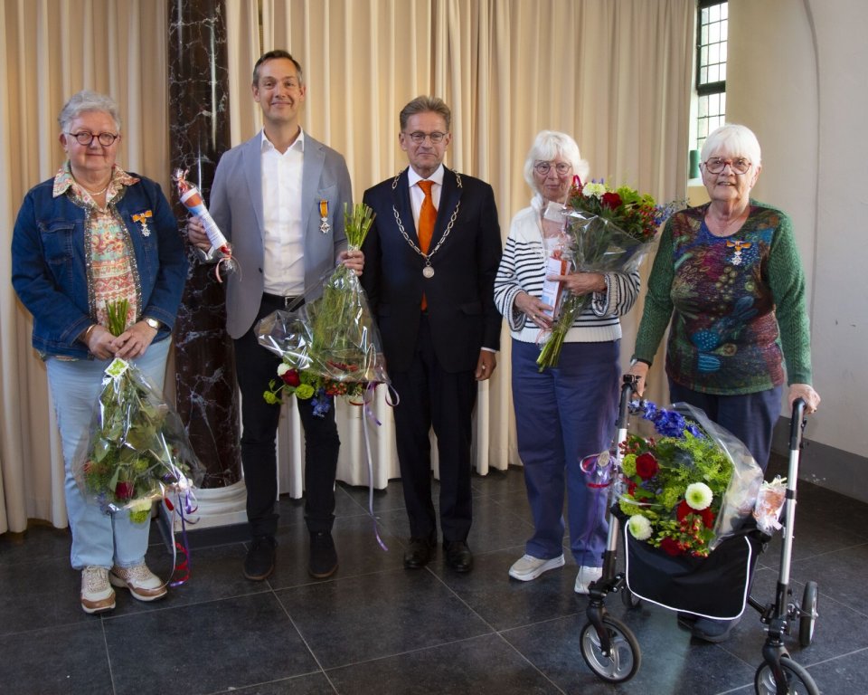 Inwoners met bloemen en burgemeester poseren voor groepsfoto