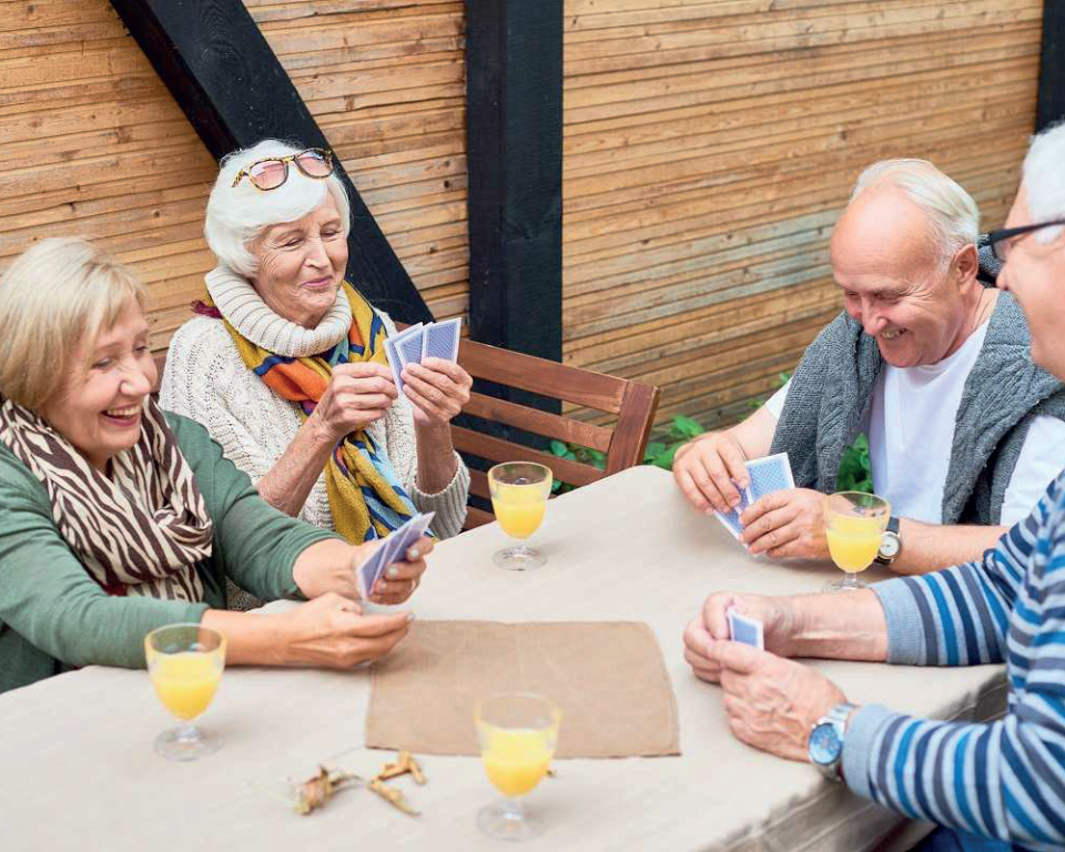 Senior mannen en vrouwen, lachend, spelen kaartspel aan een tafel