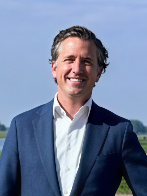 Man, lachend in blauwe pakjas met rivier en groen gras op achtergrond