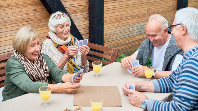 Senior mannen en vrouwen, lachend, spelen kaartspel aan een tafel