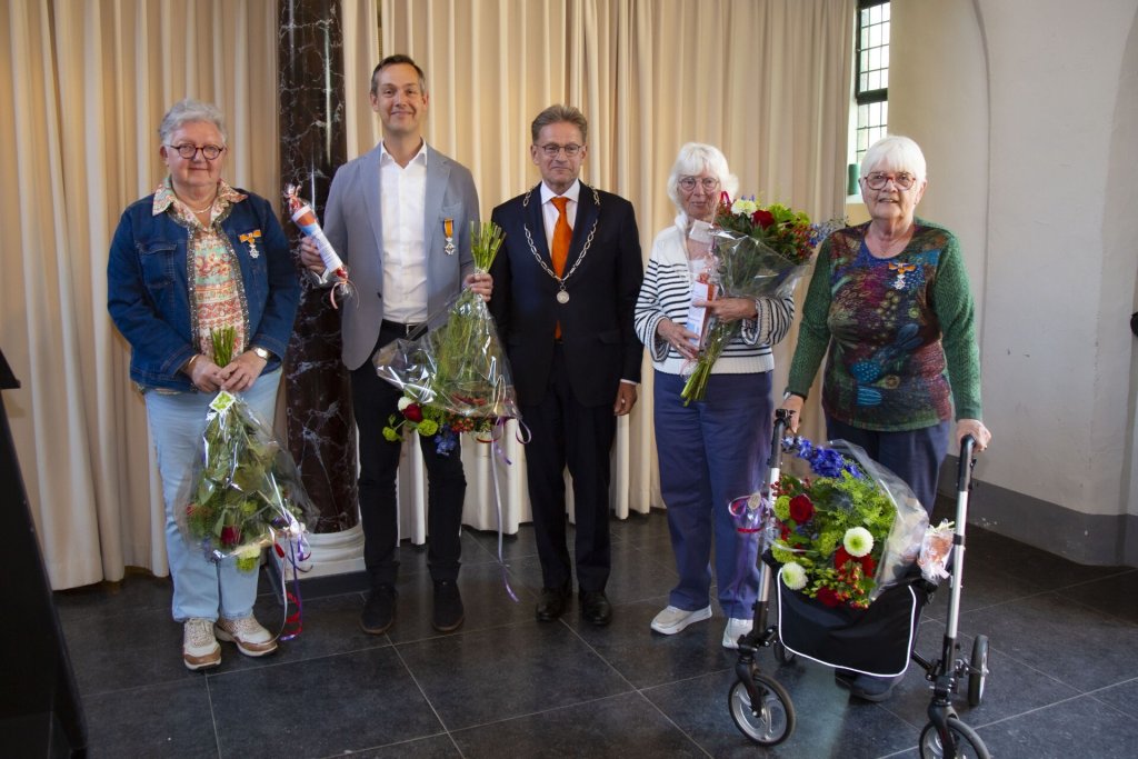 Inwoners met bloemen en burgemeester poseren voor groepsfoto