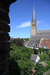 Tuinen, panden en kerktoren, blauwe lucht
