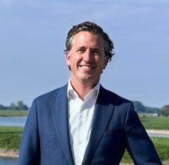 Man, lachend in blauwe pakjas met rivier en groen gras op achtergrond