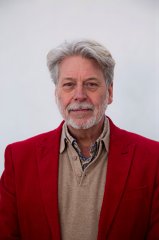 Profielfoto man middelbare leeftijd, grijs baardje, overhemd met beige sweater en rode pakjas