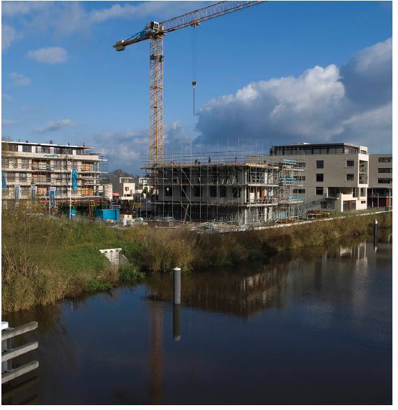 Bouwterrein met woningen in aanbouw en een grote hijskraan achter de bebouwing. Op de voorgrond de Oude IJssel