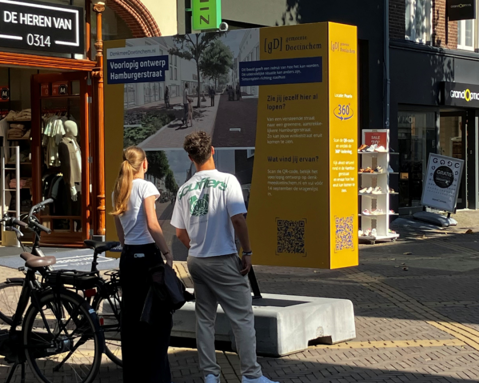 Een stel staat bij het bord voorlopig ontwerp Hamburgerstraat