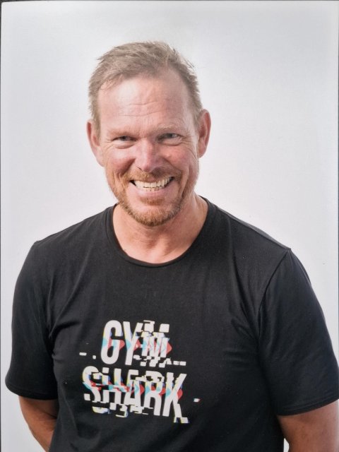 Lachende man met getrimde baard en snor in een antraciet t-shirt met korte mouwen