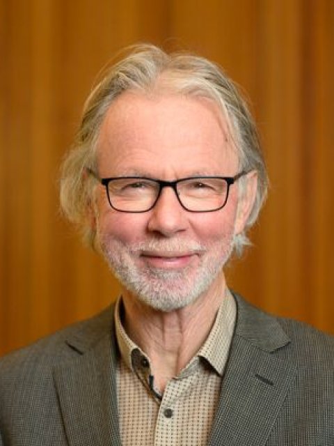 Jan Verhoeven. Man met bril, korte baard en snor. Lacht.