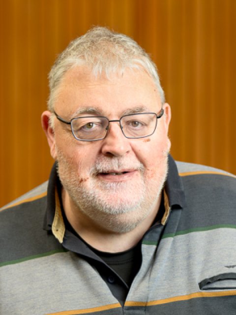 Johan van der Werf. Man met kortgeknipt grijs haar, korte baard en snor met een bril.