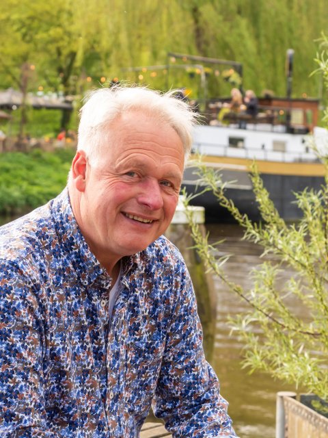 Ruud zit voor de Oude IJssel met op de achtergrond een schip.