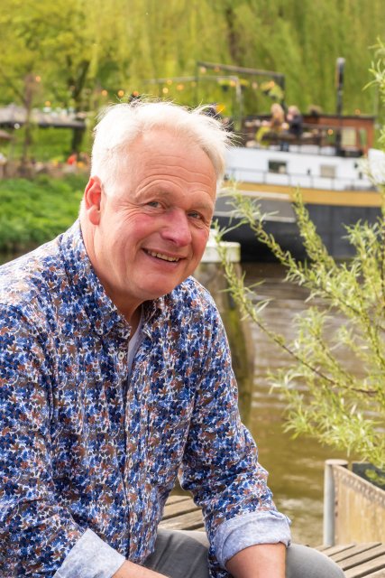 Ruud zit voor de Oude IJssel met op de achtergrond een schip.