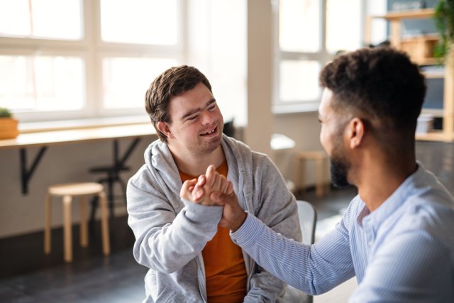 2 mannen die zitten en elkaar de hand schudden.