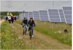 foto van 2 fietsers in een weiland naast een rij zonnepanelen