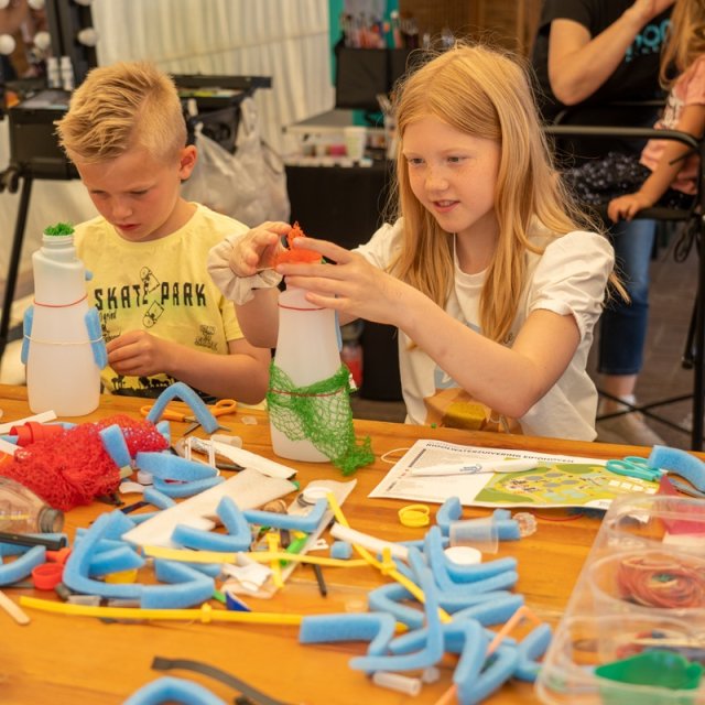 Kinderen knutselen met afval onder leiding van de Afvaljuf op de open dag Zondag Waterdag van het waterschap