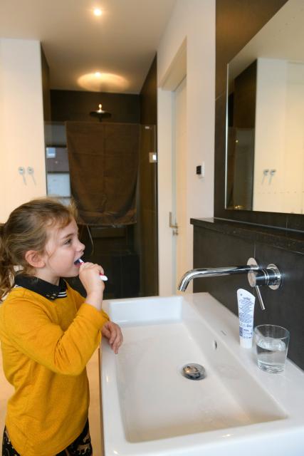 Kind poetst tanden met kraan dicht