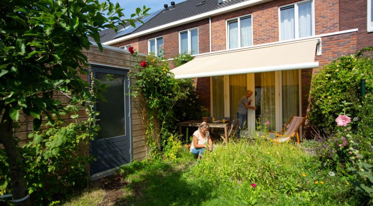 Vrouw werkt in haar tuin onder zonwering