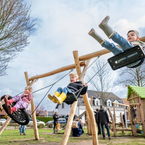 Drie kinderen aan het schommelen, elk op een eigen schommel naast elkaar