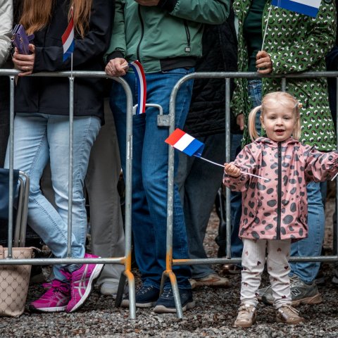 Kindje zwaait met twee Nederlandse vlaggetjes