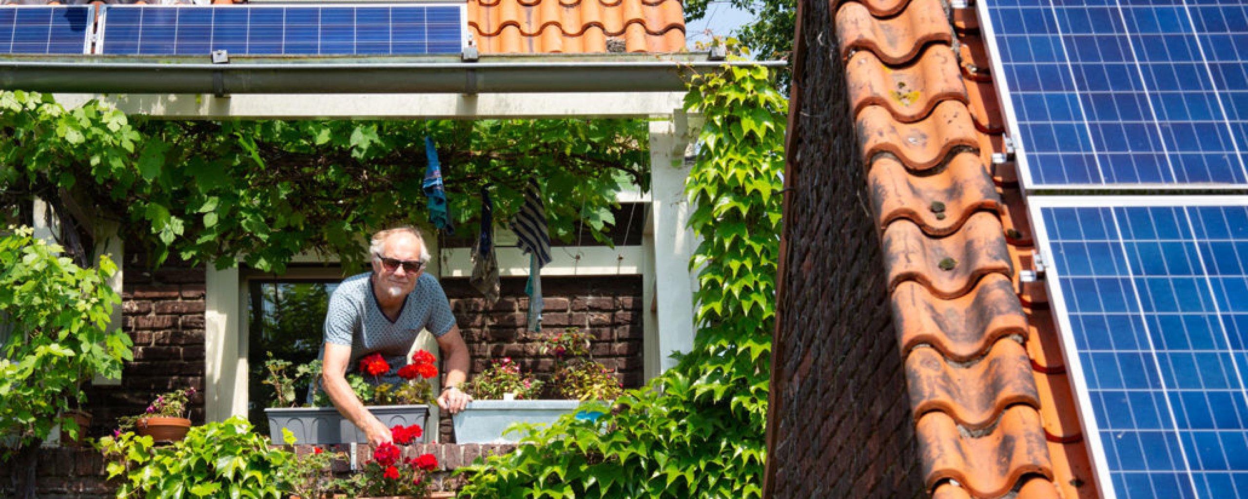 Man verzorgd bloemen op zijn balkon