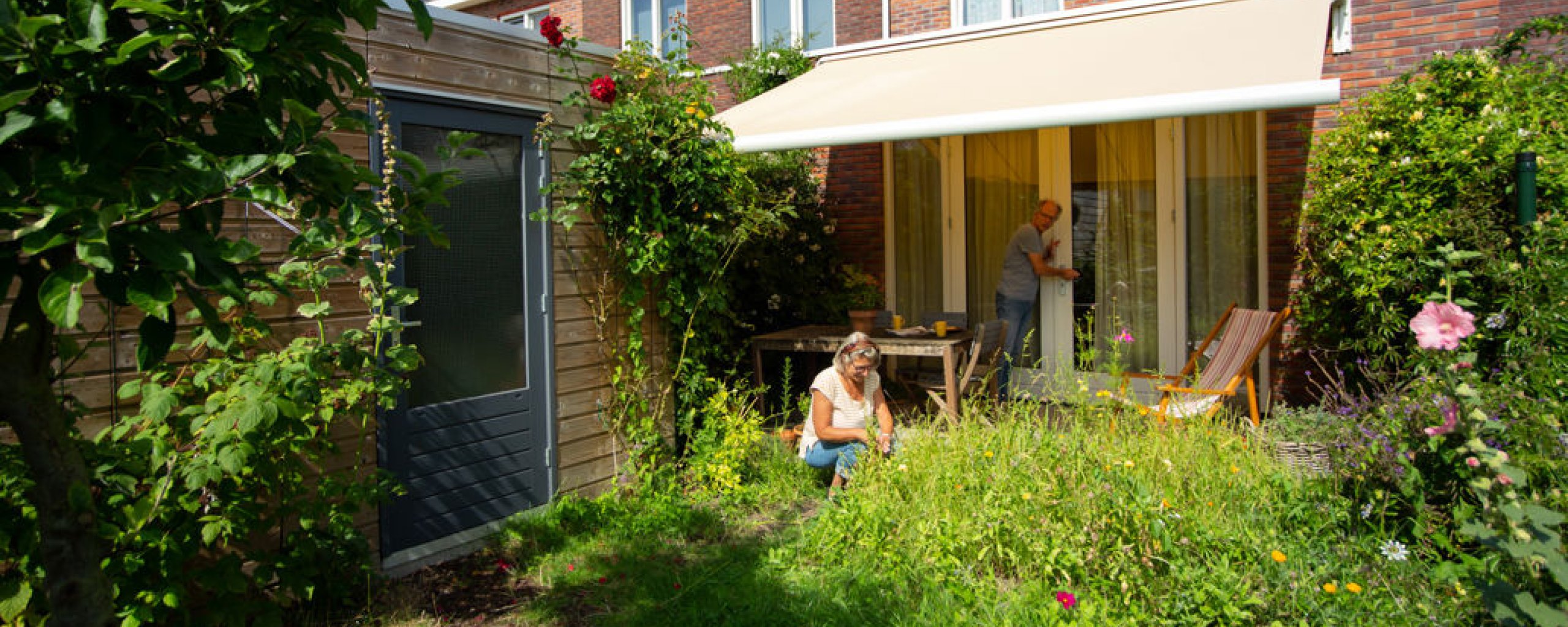 Vrouw werkt in haar tuin onder zonwering