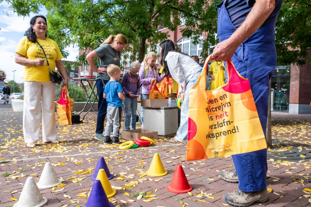 Wethouder Inge Minkenberg met enkele kinderen die spellen spelen op straat