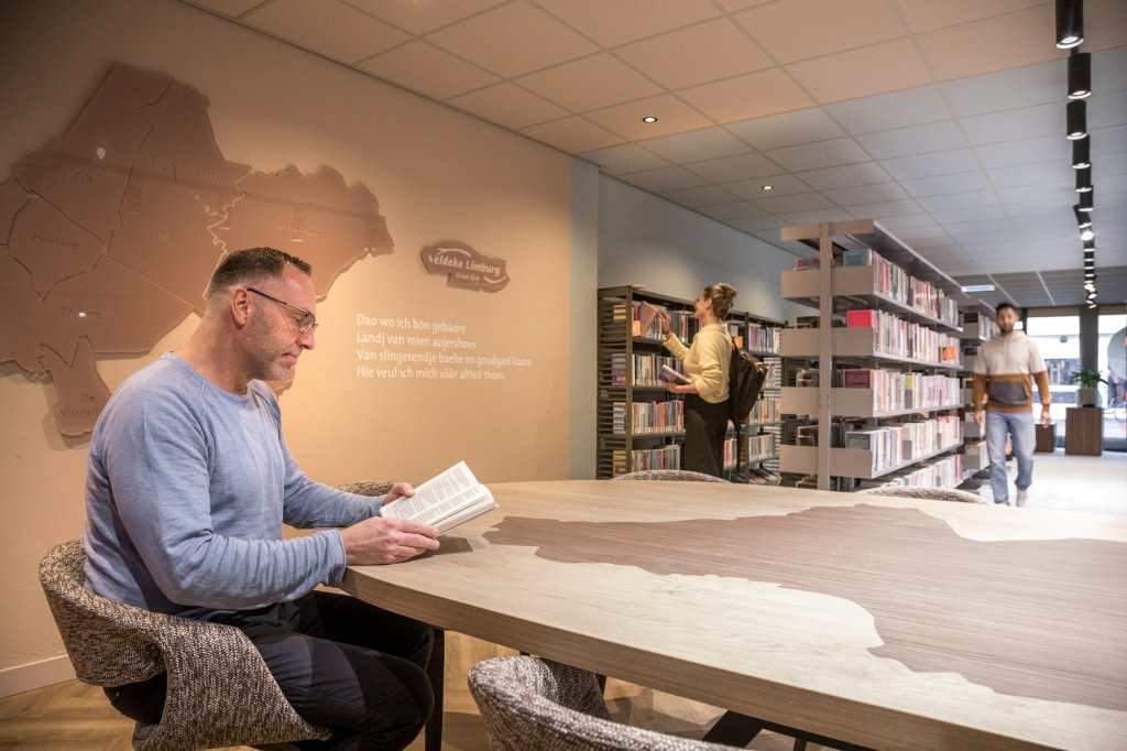 Man leest aan tafel een boek in de Bieb
