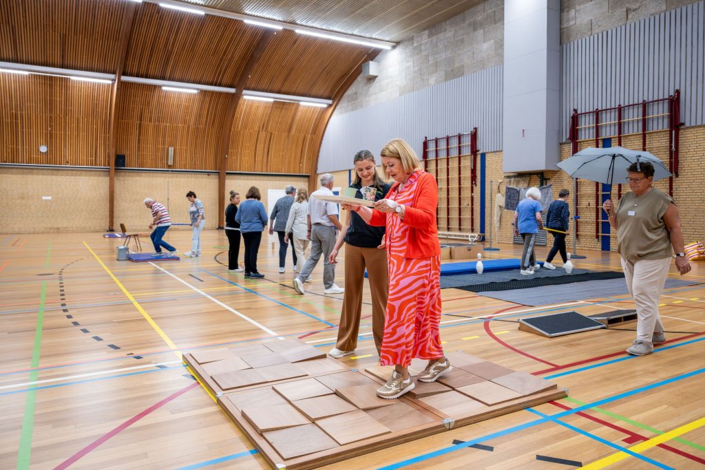 Sporthal waarin deelnemers verschillende valpreventie-oefeningen doen