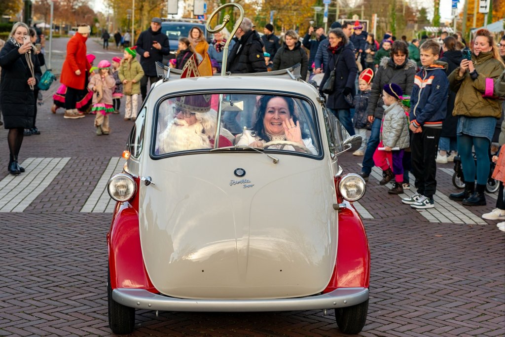 Wethouder Inge Minkenberg rijdt Sinterklaas in een klein autootje langs het publiek