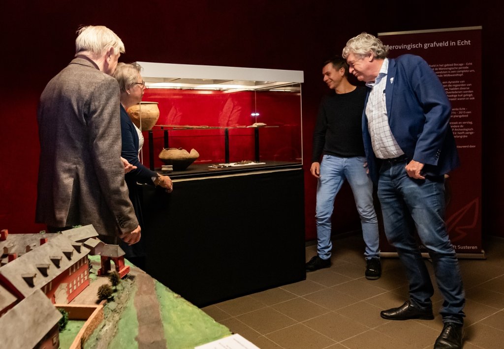 Wethouder Peter Pustjens en archeoloog Marc Ruijters bekijken een archeologische vondst in glazen kast