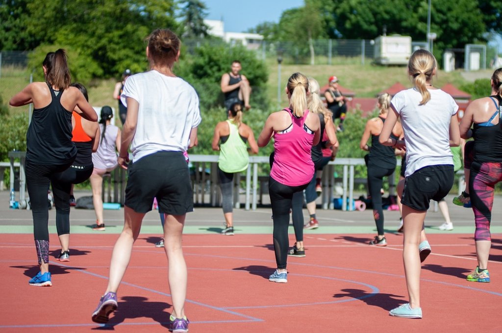 Groepje sporters doet bewegingsoefeningen onder leiding van een instructeur