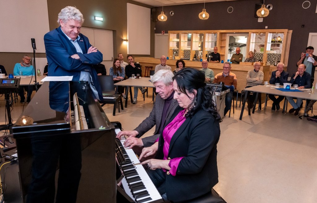 Wethouder Peter Pustjens kijk toe hoe wethouder Inge Minkenberg naast een pianist piano speelt