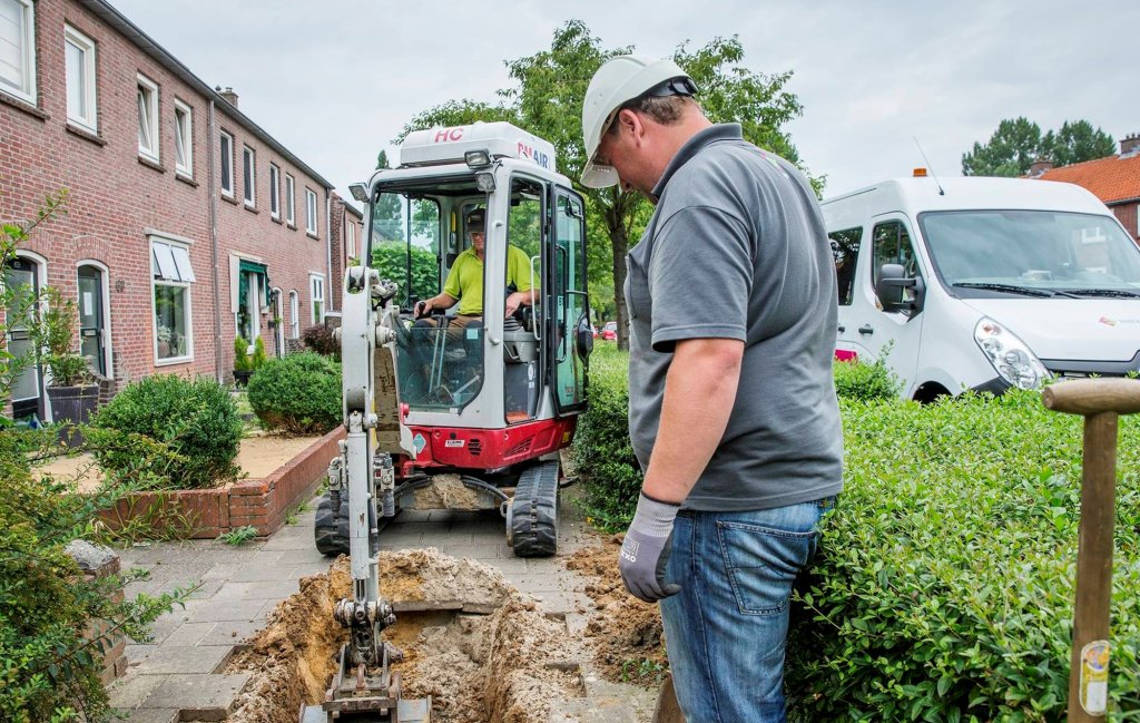 Kleine graafmachine graaft in de stoep