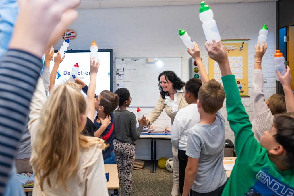 Wethouder Inge Minkenberg deelt in een klas bidons uit aan de kinderen