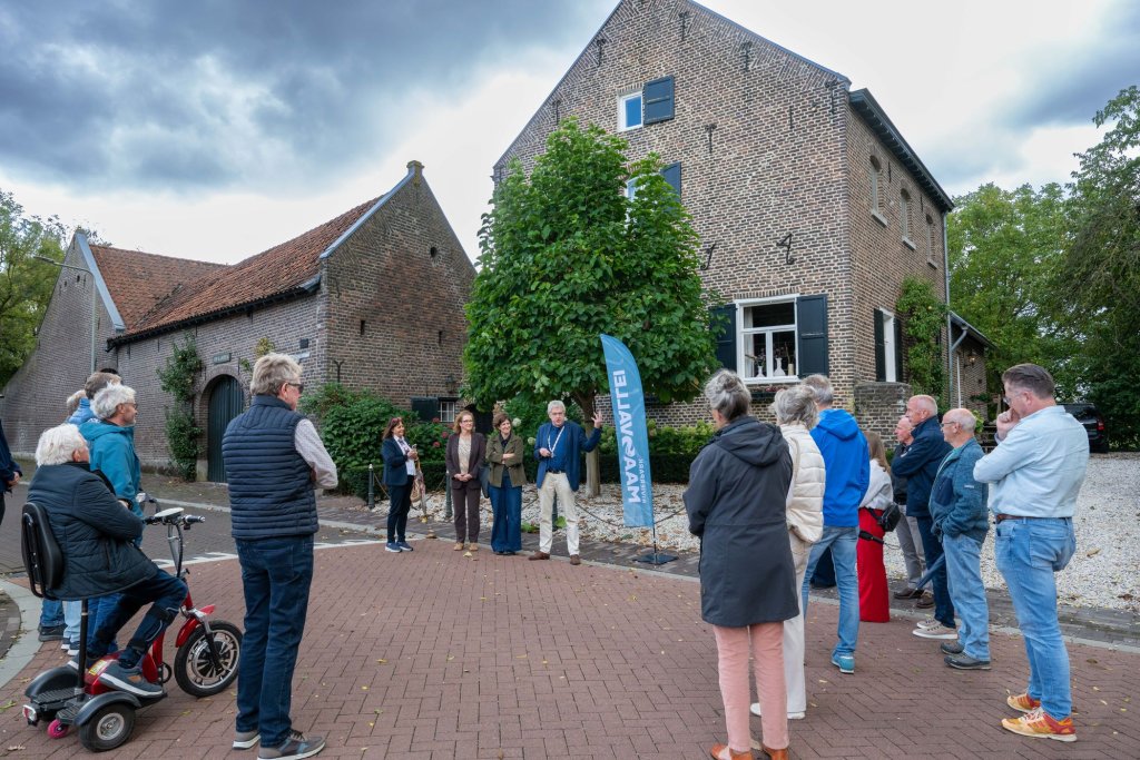 Wandelaars staan stil op straat op een bijzondere plek in Roosteren