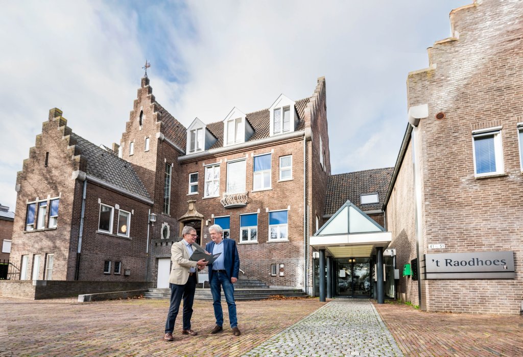 Wethouder Pustjens en wethouder Meuwissen bij het voormalige gemeentehuis in Susteren