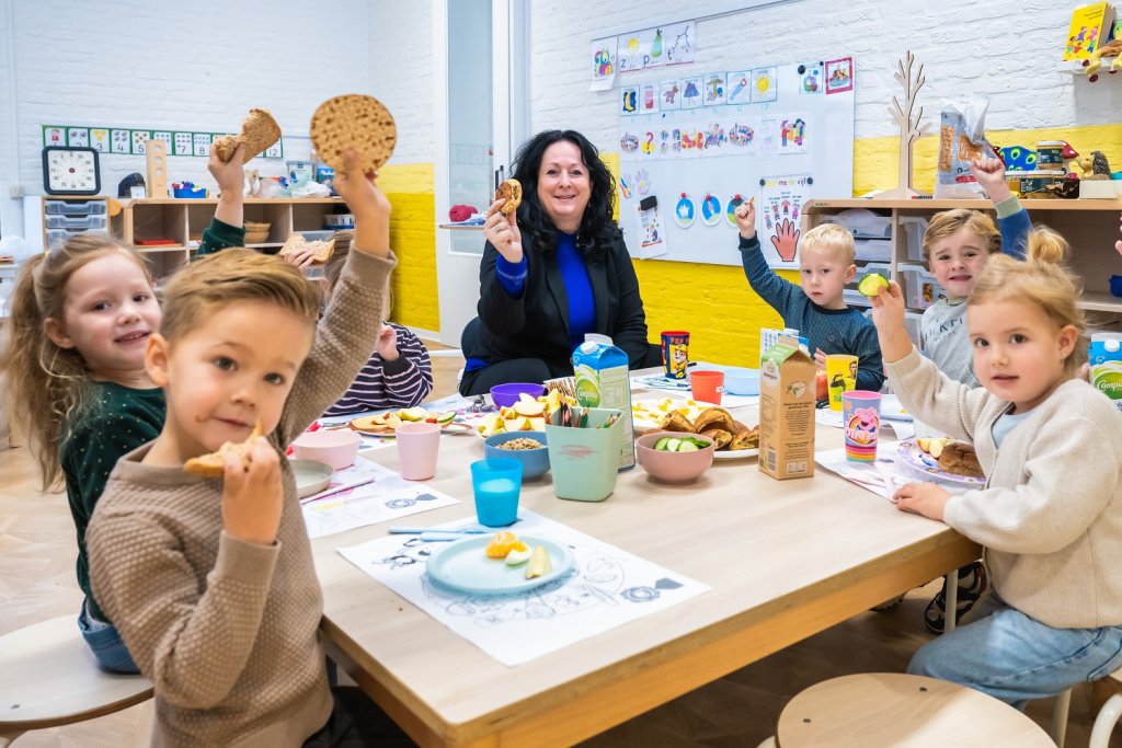 Wethouder Inge Minkenberg samen met enkele kinderen aan het schoolontbijt