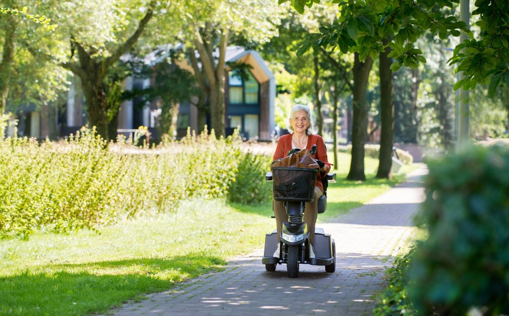 Seniore dame op een scootmobiel in bosrijke omgeving