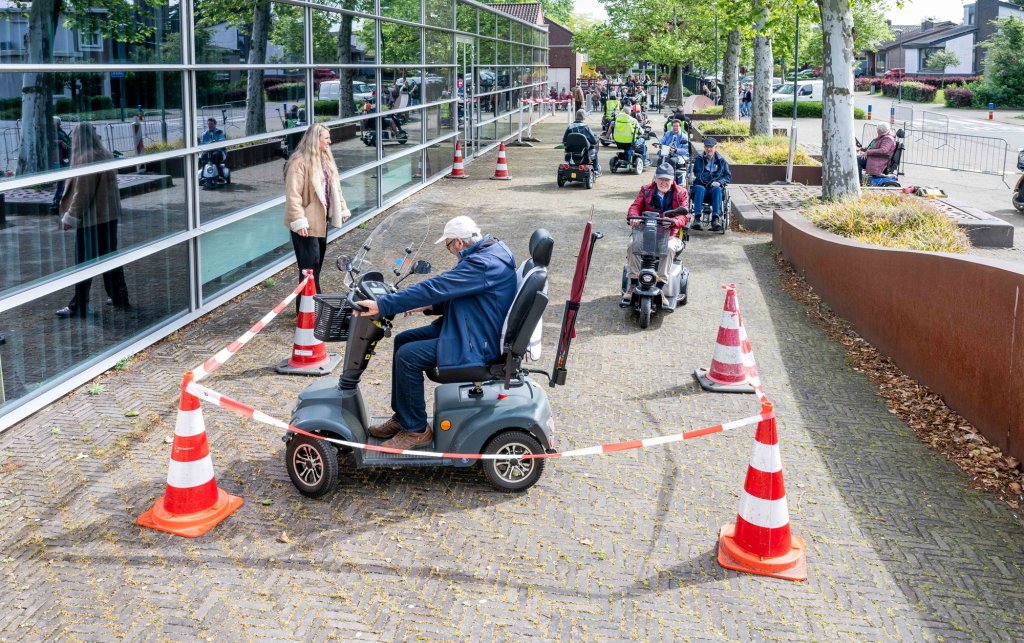 Senioren rijden een parcours met hun scootmobiel