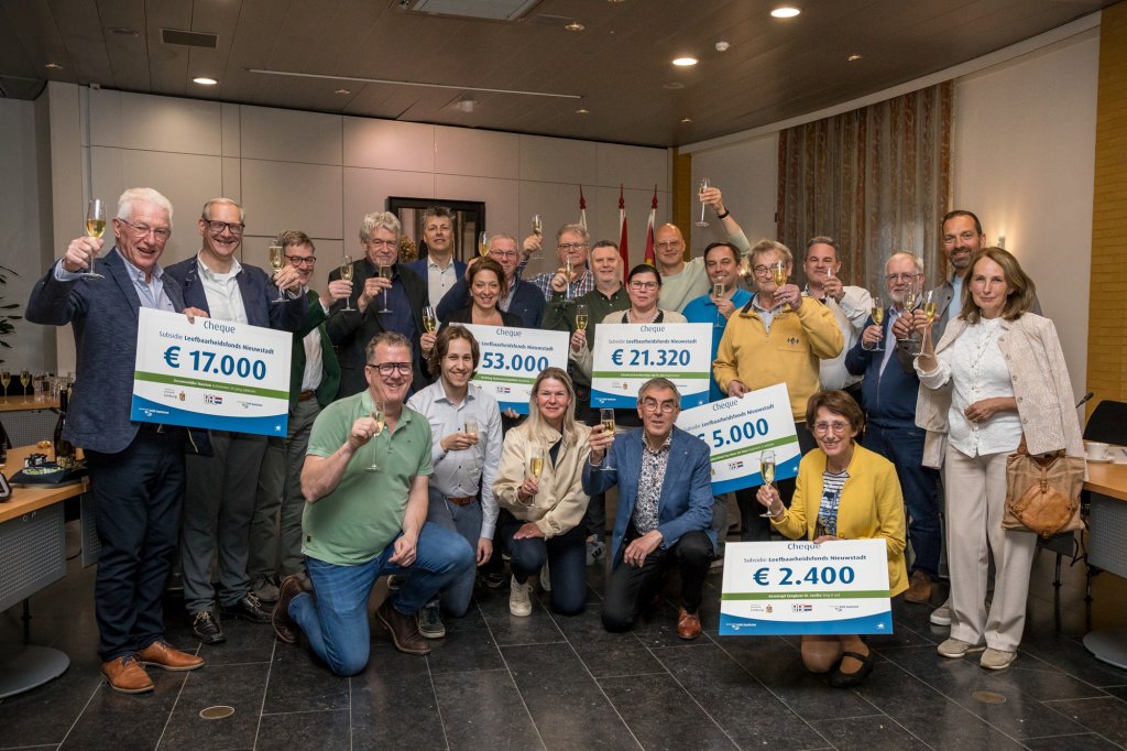 Groepsfoto van verenigingsleden met symbolische cheques van het Leefbaarheidsfonds Nieuwstadt