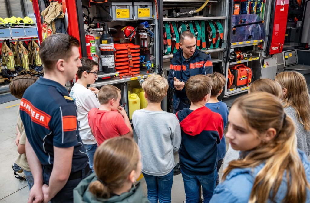 Twee brandweermannen geven uitleg over het materiaal in de brandweerkazerne