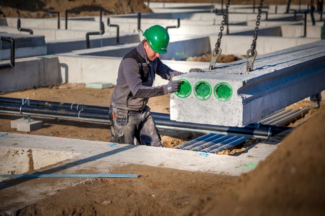 Bouwvakker met groene helm plaatst betonnen element