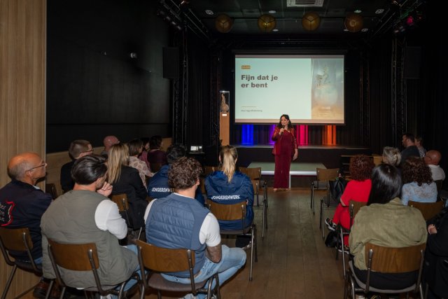 Zaal met mensen die luisteren naar een presentatie